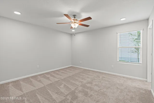 an empty room with windows and fan