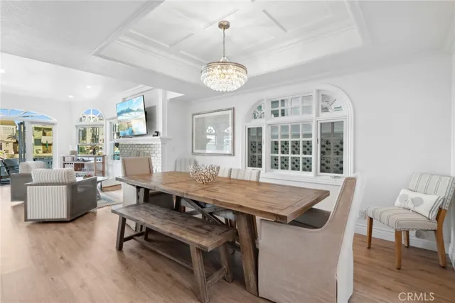 a dining room with wooden floor a chandelier a wooden table and chairs