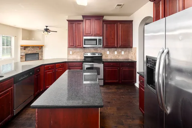 a kitchen with stainless steel appliances granite countertop a refrigerator a sink a stove a microwave and island