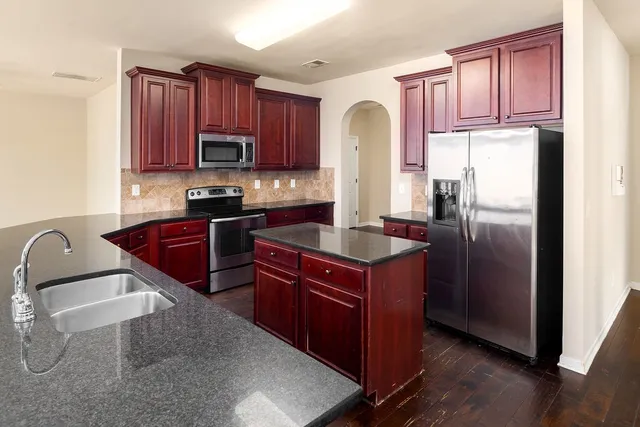 a kitchen with stainless steel appliances granite countertop a refrigerator a stove a sink and a microwave