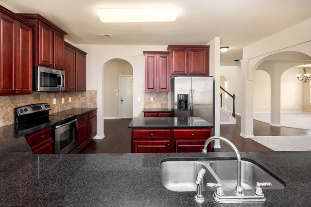 a kitchen with stainless steel appliances granite countertop a stove a sink and a microwave