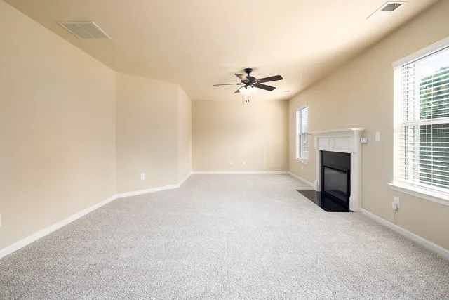 an empty room with windows and fireplace