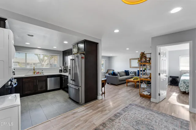 a kitchen with stainless steel appliances kitchen island granite countertop a refrigerator and a sink