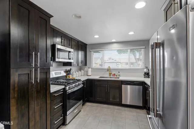 a kitchen with stainless steel appliances granite countertop sink stove and refrigerator
