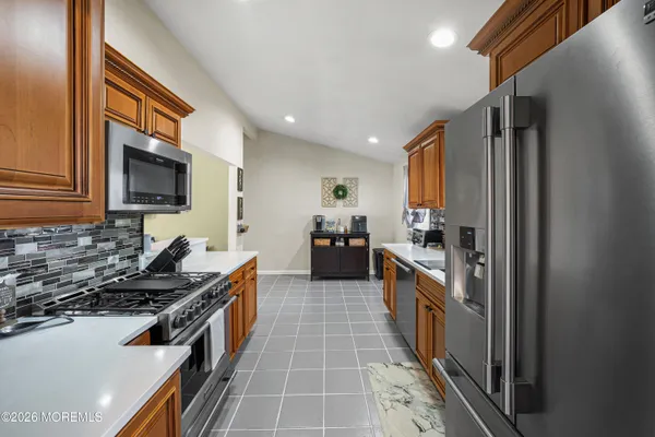 a kitchen with stainless steel appliances granite countertop a stove top oven a sink and a refrigerator