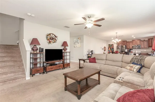 a living room with furniture a ceiling fan and a flat screen tv