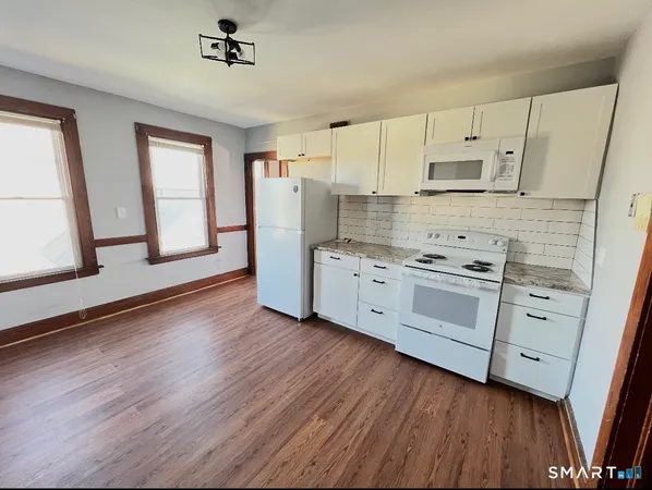 a kitchen with white cabinets stainless steel appliances and wooden floor