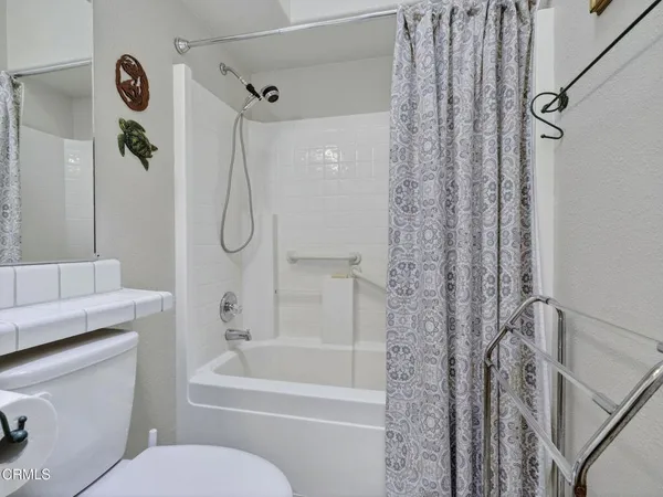 a bathroom with a granite countertop bathtub shower sink vanity and toilet