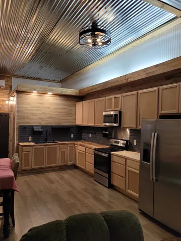 a kitchen with stainless steel appliances kitchen island granite countertop a refrigerator a stove and a sink