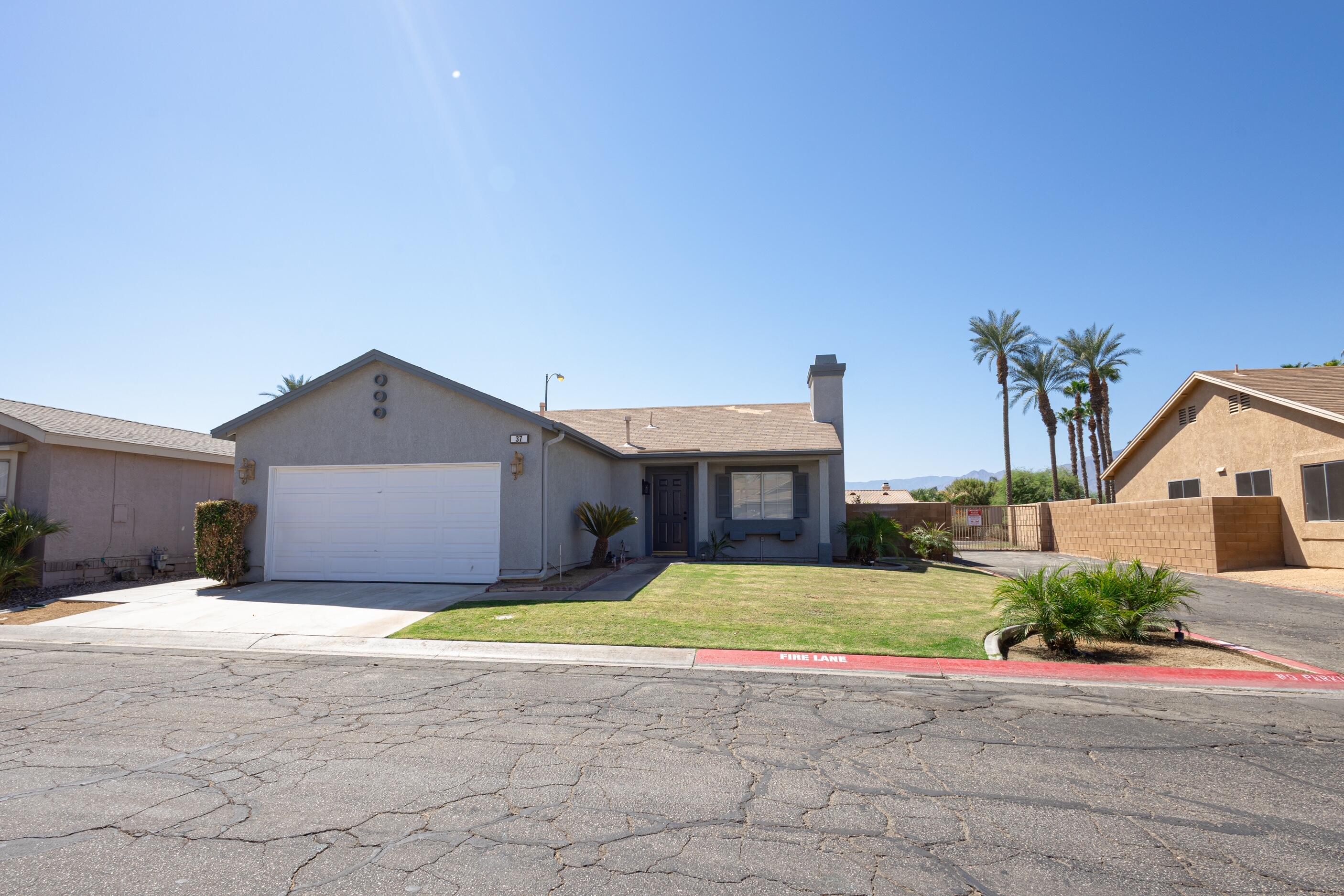 47800 Madison Street, Unit 37 Indio, CA 92201 - Photo 1 of 15 a view of a house with a yard and a large parking space
