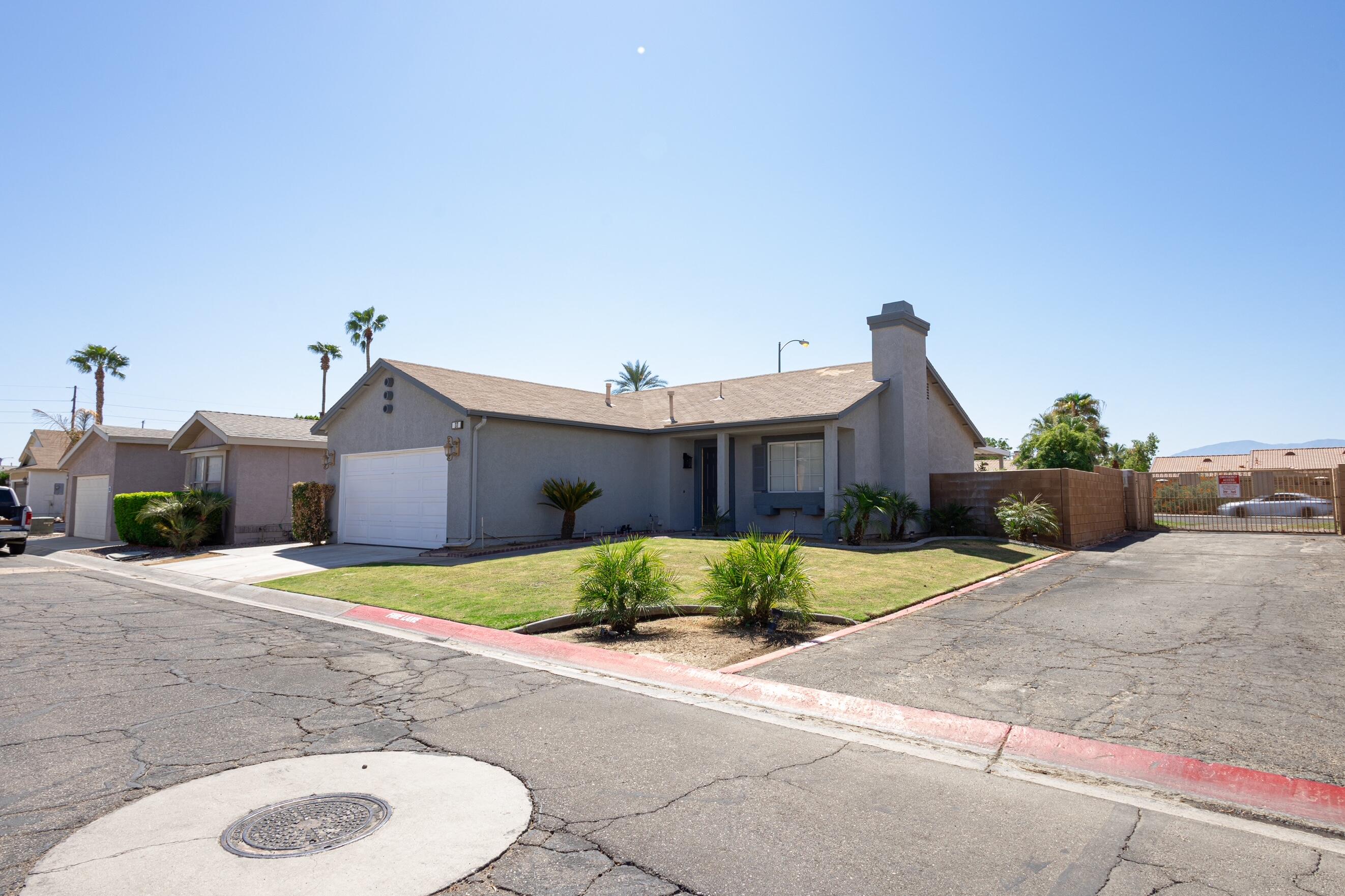 47800 Madison Street, Unit 37 Indio, CA 92201 - Photo 4 of 15 a front view of a house with a yard and garage