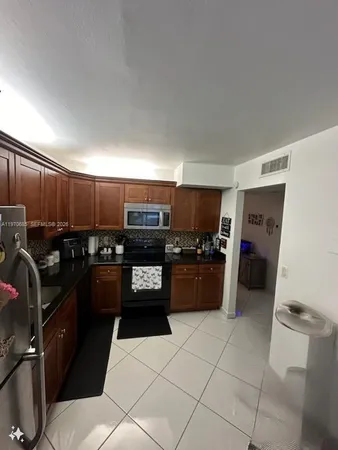 a kitchen with granite countertop a refrigerator and a stove top oven