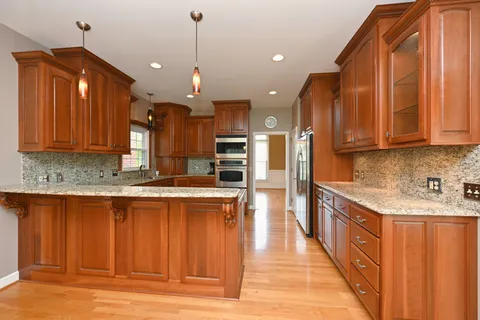 a large kitchen with stainless steel appliances kitchen island granite countertop a stove a sink dishwasher and a refrigerator with wooden cabinets
