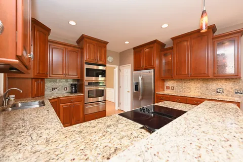 a kitchen with stainless steel appliances kitchen island granite countertop a refrigerator and a stove top oven