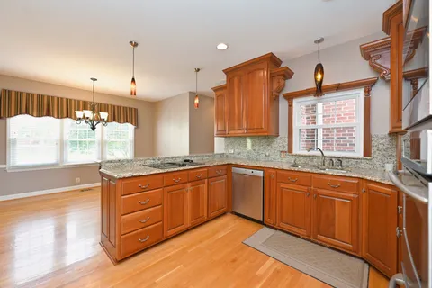 a kitchen with stainless steel appliances granite countertop a sink and cabinets with wooden floor