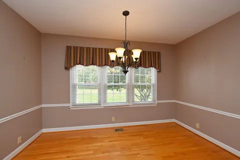 a view of an empty room with chandelier fan and fire place