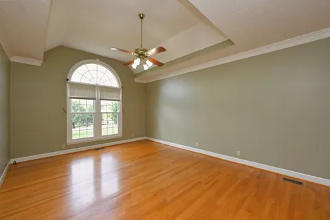 an empty room with wooden floor fan and windows