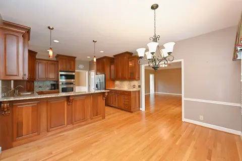 a large kitchen with granite countertop a stove a sink and a wooden floors