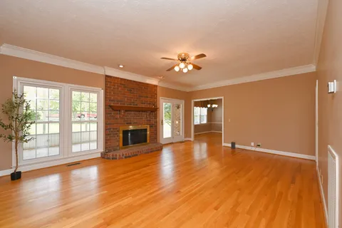 a view of an empty room with a window and wooden floor