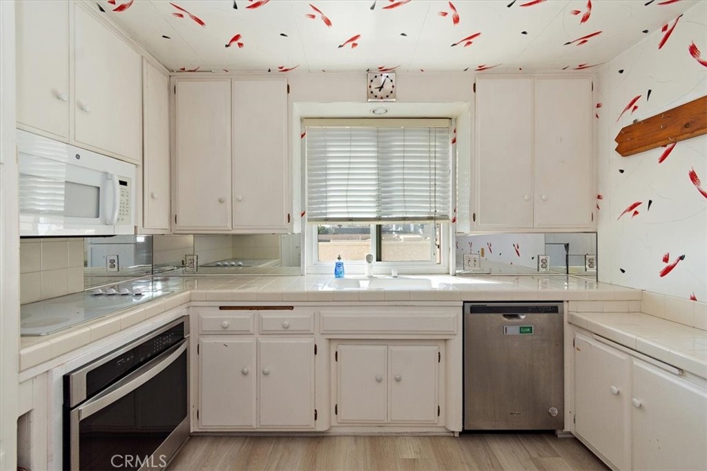 21 7th Place, Unit 409 Long Beach, CA 90802 - Photo 7 of 16 a kitchen with a sink stove cabinets and wooden floor