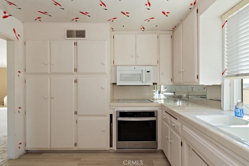 21 7th Place, Unit 409 Long Beach, CA 90802 - Photo 8 of 16 a kitchen with granite countertop white cabinets and stainless steel appliances