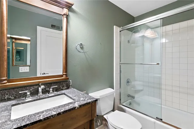 a bathroom with a granite countertop sink toilet a mirror and shower