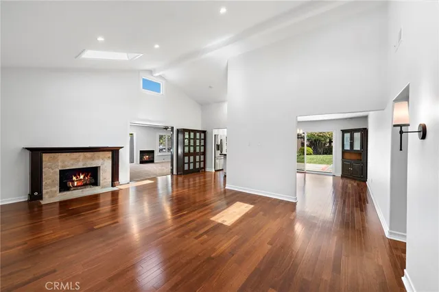 an empty room with wooden floor fireplace and windows