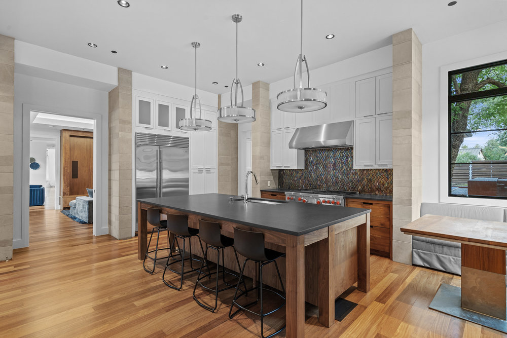 1905 Paisano Road Austin, TX 78746 - Photo 9 of 40 A gourmet kitchen offers abundant space for culinary creation, anchored by a large center island and a full suite of professional-grade appliances.