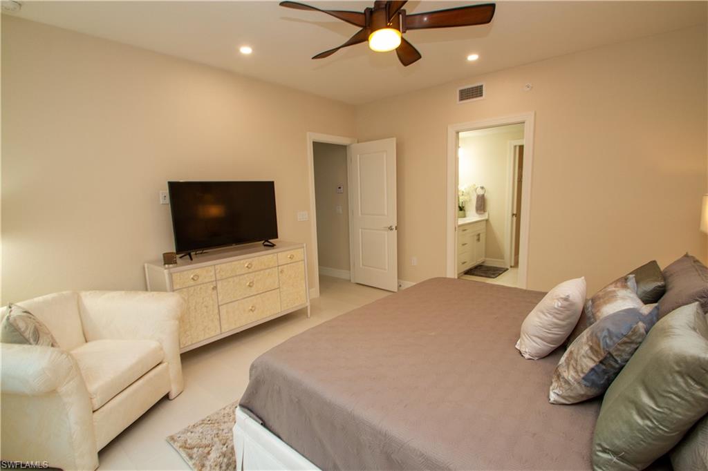 262 Indies Drive East, Unit 101 Naples, FL 34114 - Photo 12 of 32 a bedroom with a bed and a flat screen tv
