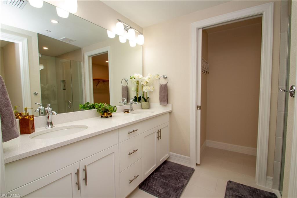 262 Indies Drive East, Unit 101 Naples, FL 34114 - Photo 13 of 32 a bathroom with a double vanity sink and a mirror
