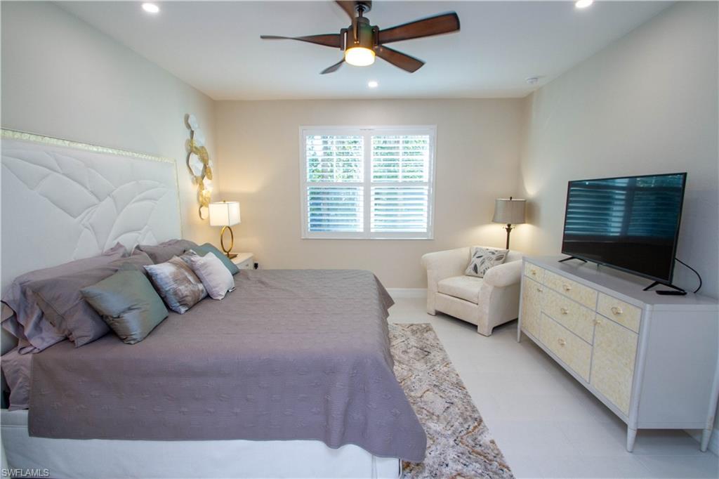 262 Indies Drive East, Unit 101 Naples, FL 34114 - Photo 14 of 32 a bedroom with a large bed and a flat screen tv
