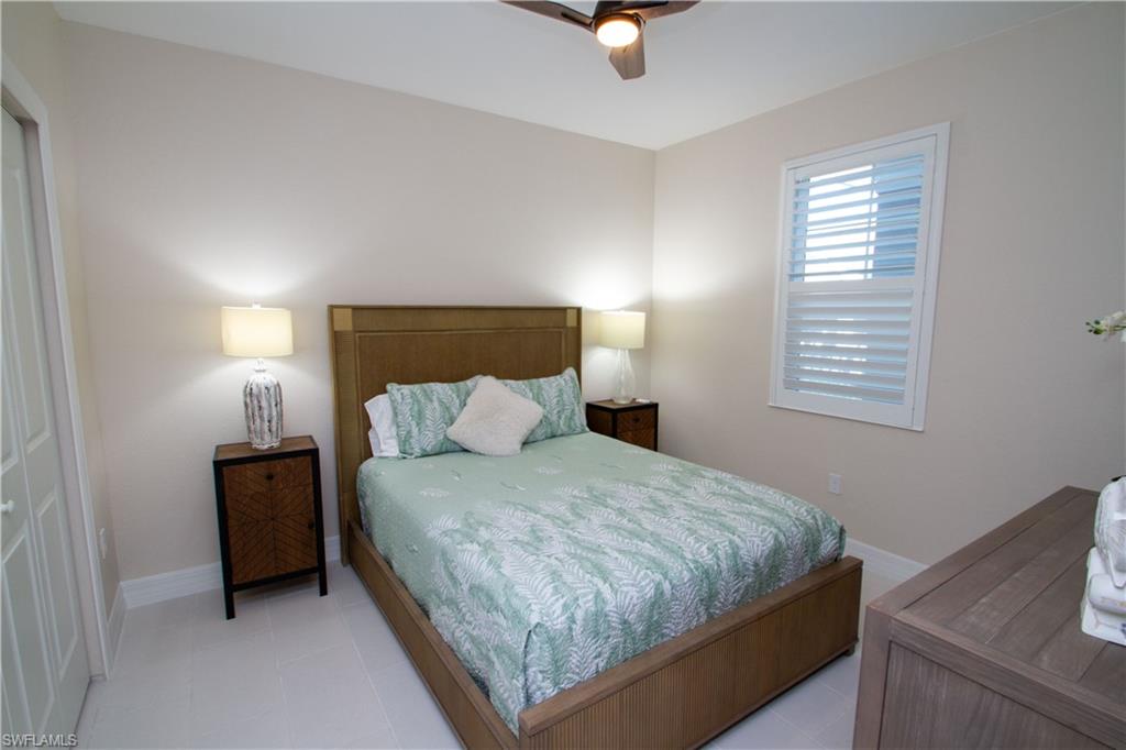 262 Indies Drive East, Unit 101 Naples, FL 34114 - Photo 15 of 32 a bedroom with a bed and a night stand