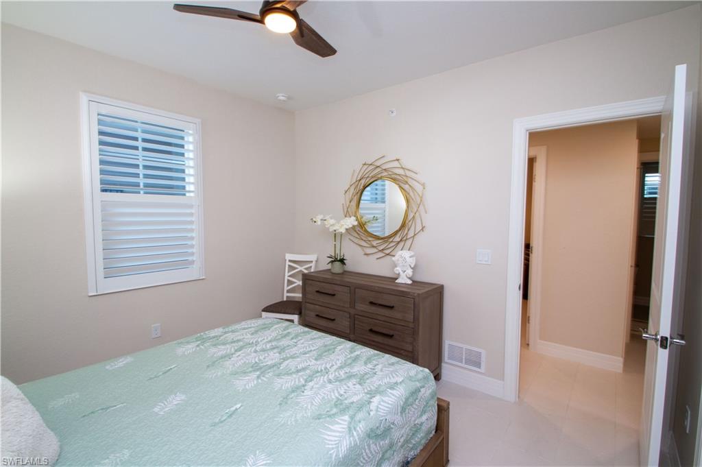 262 Indies Drive East, Unit 101 Naples, FL 34114 - Photo 17 of 32 a bed room with a bed closet and mirror