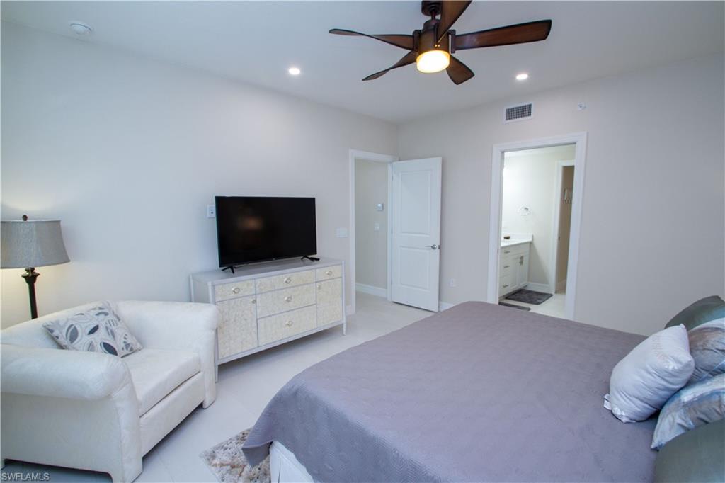 262 Indies Drive East, Unit 101 Naples, FL 34114 - Photo 9 of 32 a bedroom with a bed and a flat screen tv