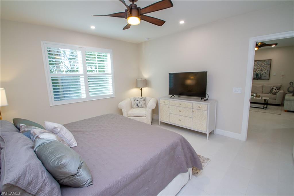 262 Indies Drive East, Unit 101 Naples, FL 34114 - Photo 10 of 32 a bedroom with a bed a window and a television