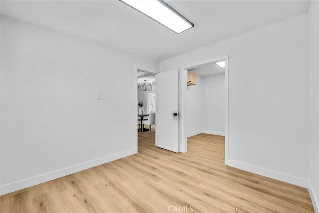 a view of an empty room with wooden floor and closet