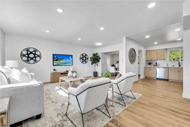 a living room with furniture and kitchen view with wooden floor