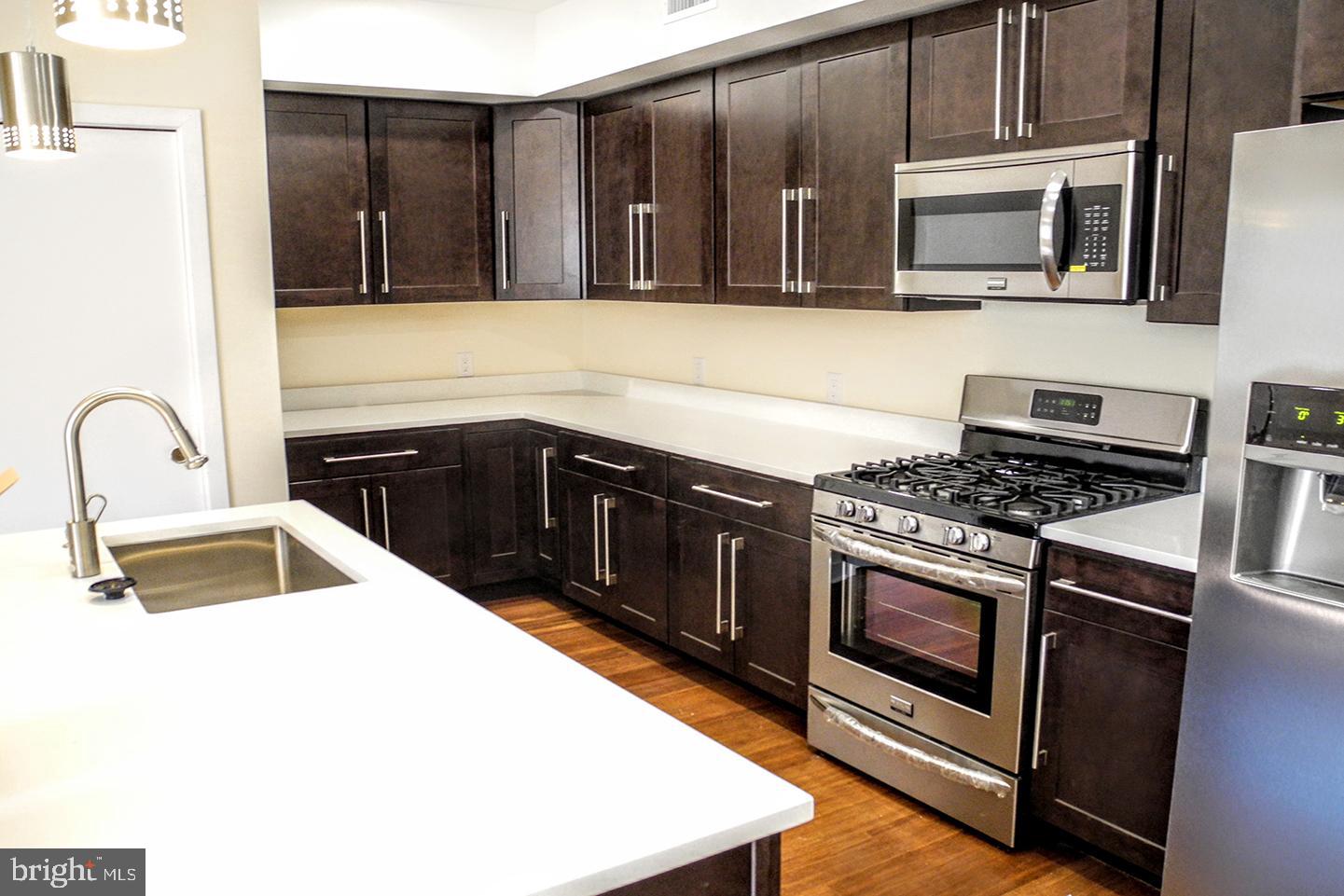 934 South 5th Street, Unit B2 Philadelphia, PA 19147 - Photo 5 of 11 a kitchen with stainless steel appliances granite countertop a stove microwave and sink