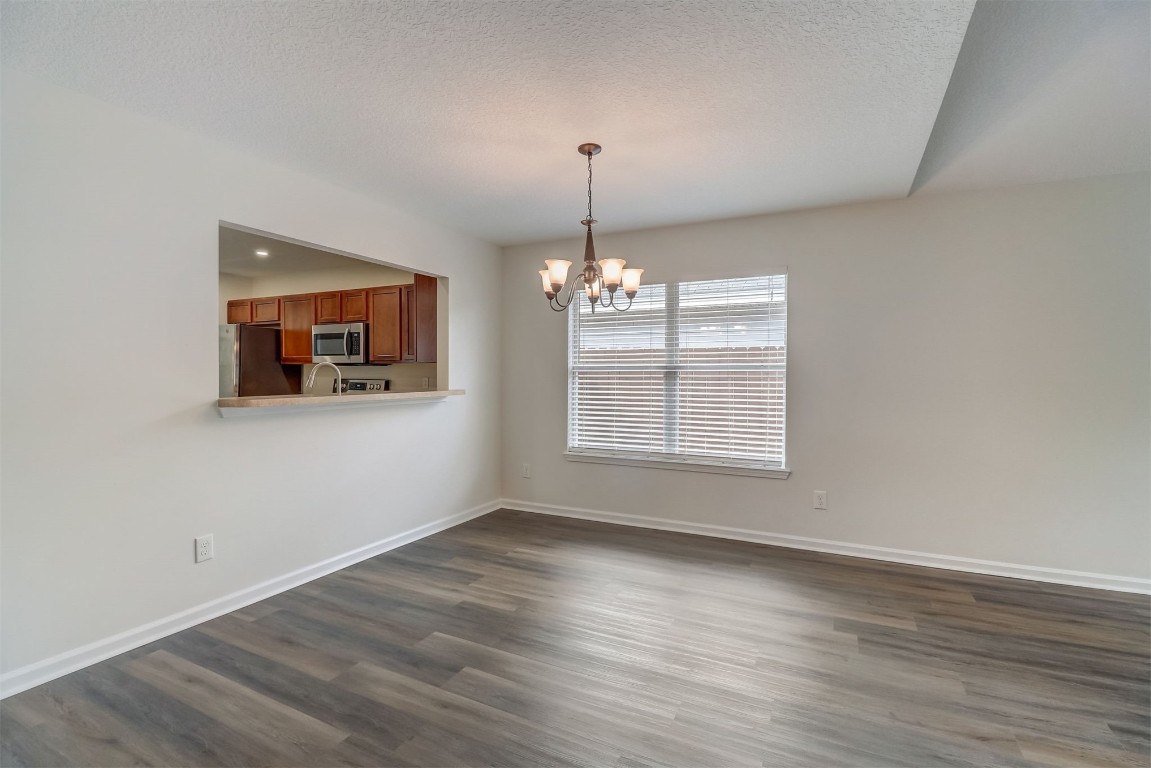 96099 Starlight Lane Yulee, FL 32097 - Photo 6 of 36 an empty room with wooden floor chandelier and windows