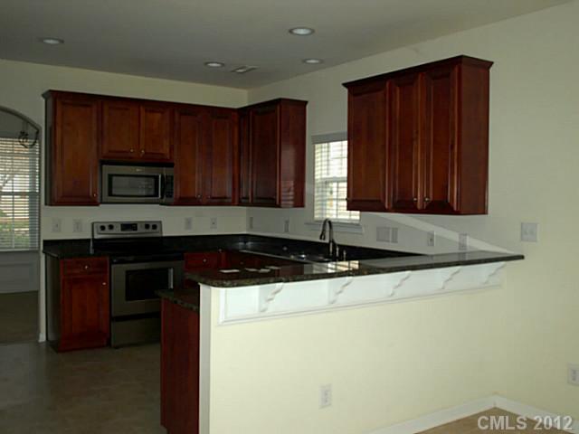 9942 Caldwell Depot Road Cornelius, NC 28031 - Photo 3 of 9 a kitchen with granite countertop wooden cabinets a stove top oven and granite counter tops