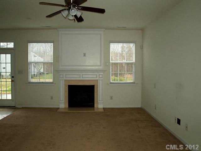 9942 Caldwell Depot Road Cornelius, NC 28031 - Photo 5 of 9 an empty room with a fireplace and windows