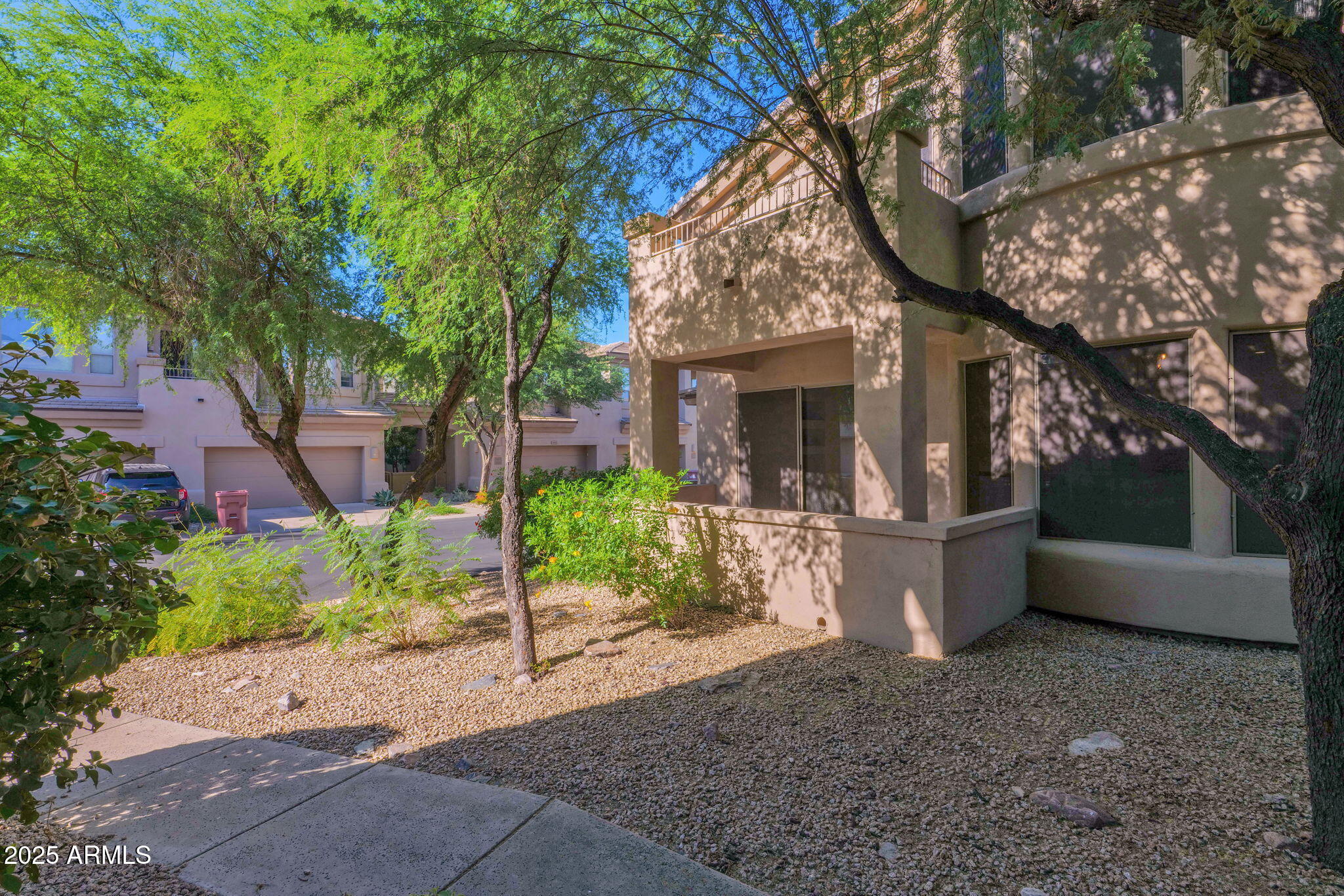 16420 North Thompson Peak Parkway, Unit 1057 Scottsdale, AZ 85260 - Photo 37 of 39 a view of a white house with a large tree and plants