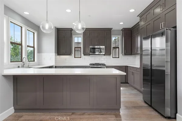 a large kitchen with a large counter top a sink stainless steel appliances and cabinets