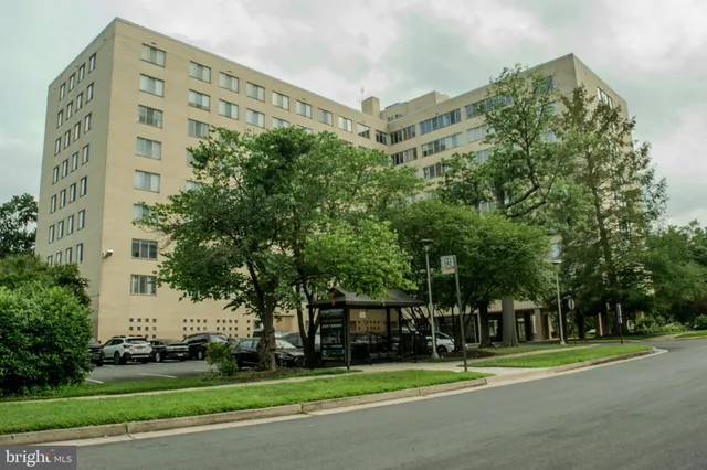 a view of a tall building with a big yard and large trees
