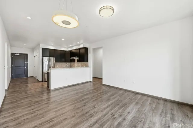 a view of a kitchen with kitchen island a sink wooden floor and a refrigerator
