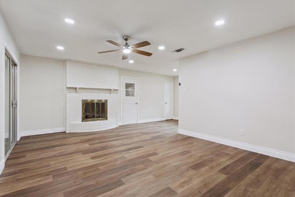 849 Arlington Drive Woodway, TX 76712 - Photo 12 of 33 an empty room with wooden floor fireplace and windows