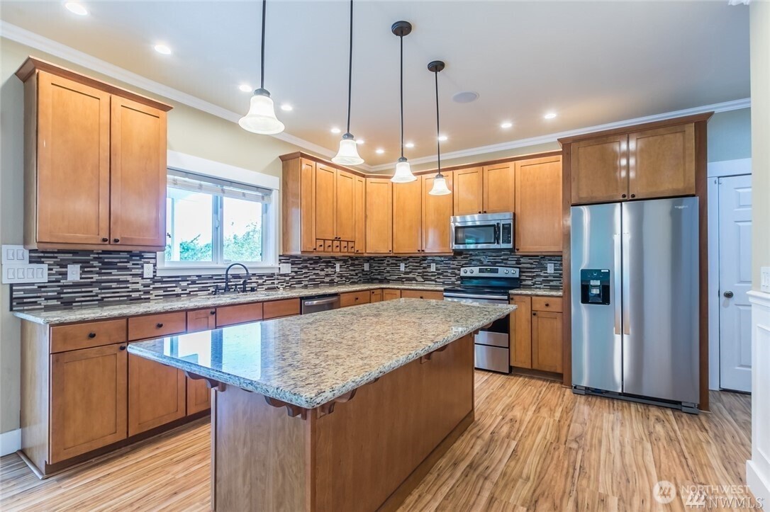 16619 249th Street East Orting, WA 98360 - Photo 5 of 21 a kitchen with stainless steel appliances granite countertop wooden floors stove and refrigerator