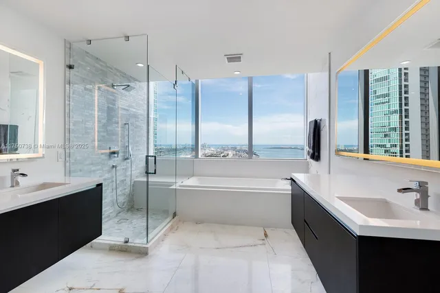 a bathroom with a double vanity sink and mirror with bathtub