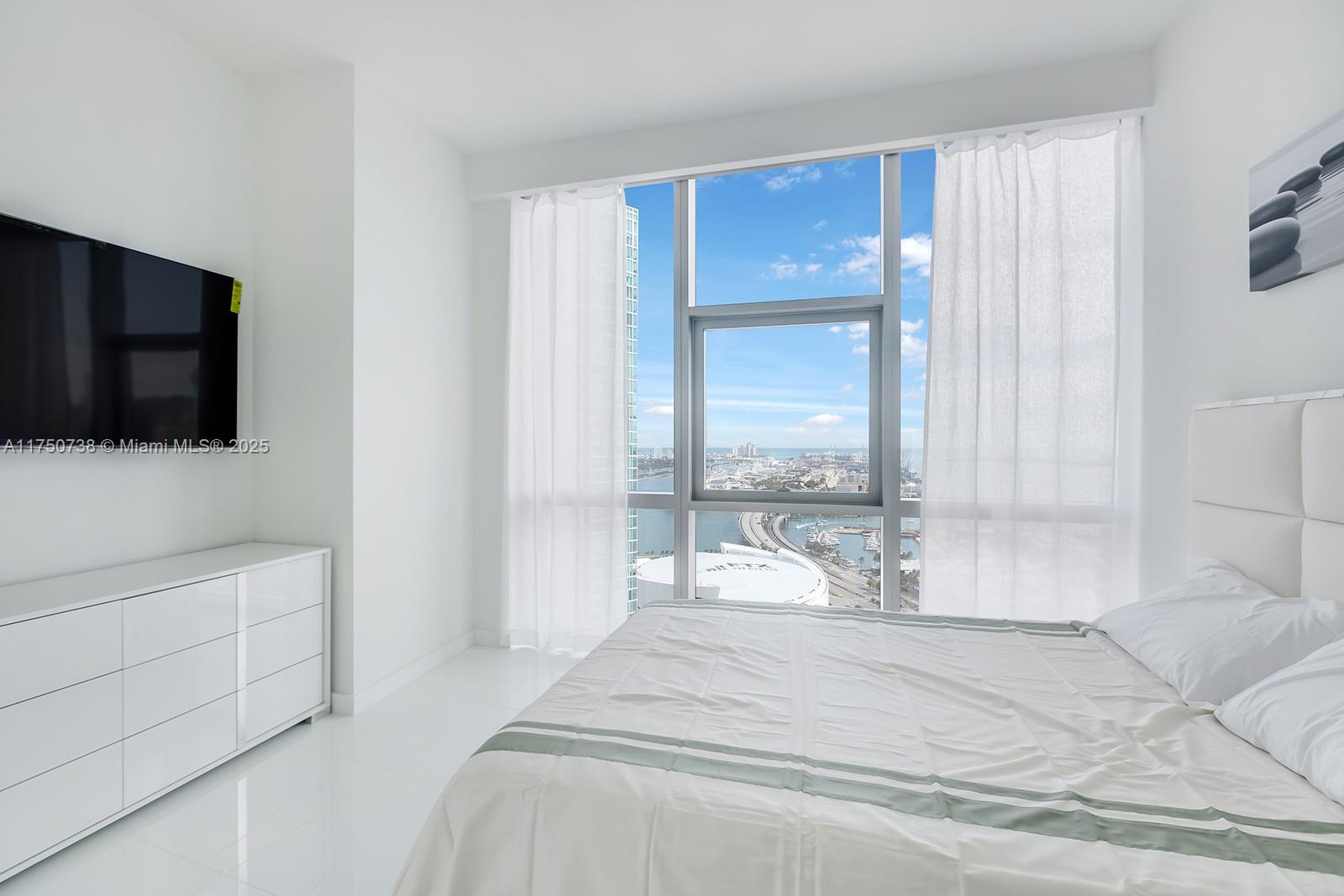 851 Northeast 1st Avenue, Unit 3611 Miami, FL 33132 - Photo 17 of 23 a bedroom with a bed and a flat screen tv