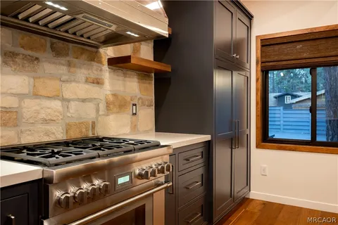 a kitchen with a sink and a stove with wooden floor